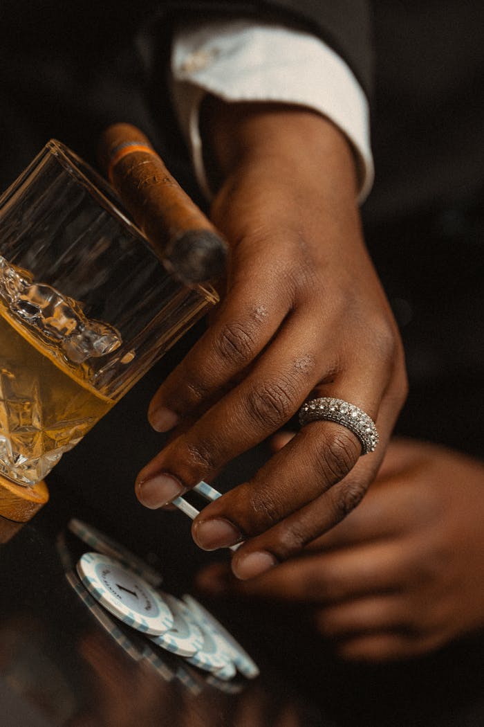 Close-up Hands above Casino Tokens and a Glass of Whisky